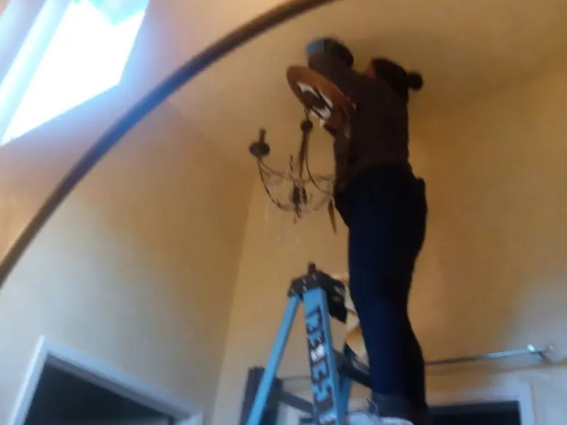 Electrician installing a chandelier in a Moorhead residence